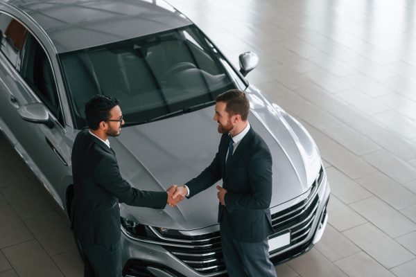 Doing handshake. Two businessmen are working together in the car showroom Doing handshake. Two businessmen are working together in the car showroom.